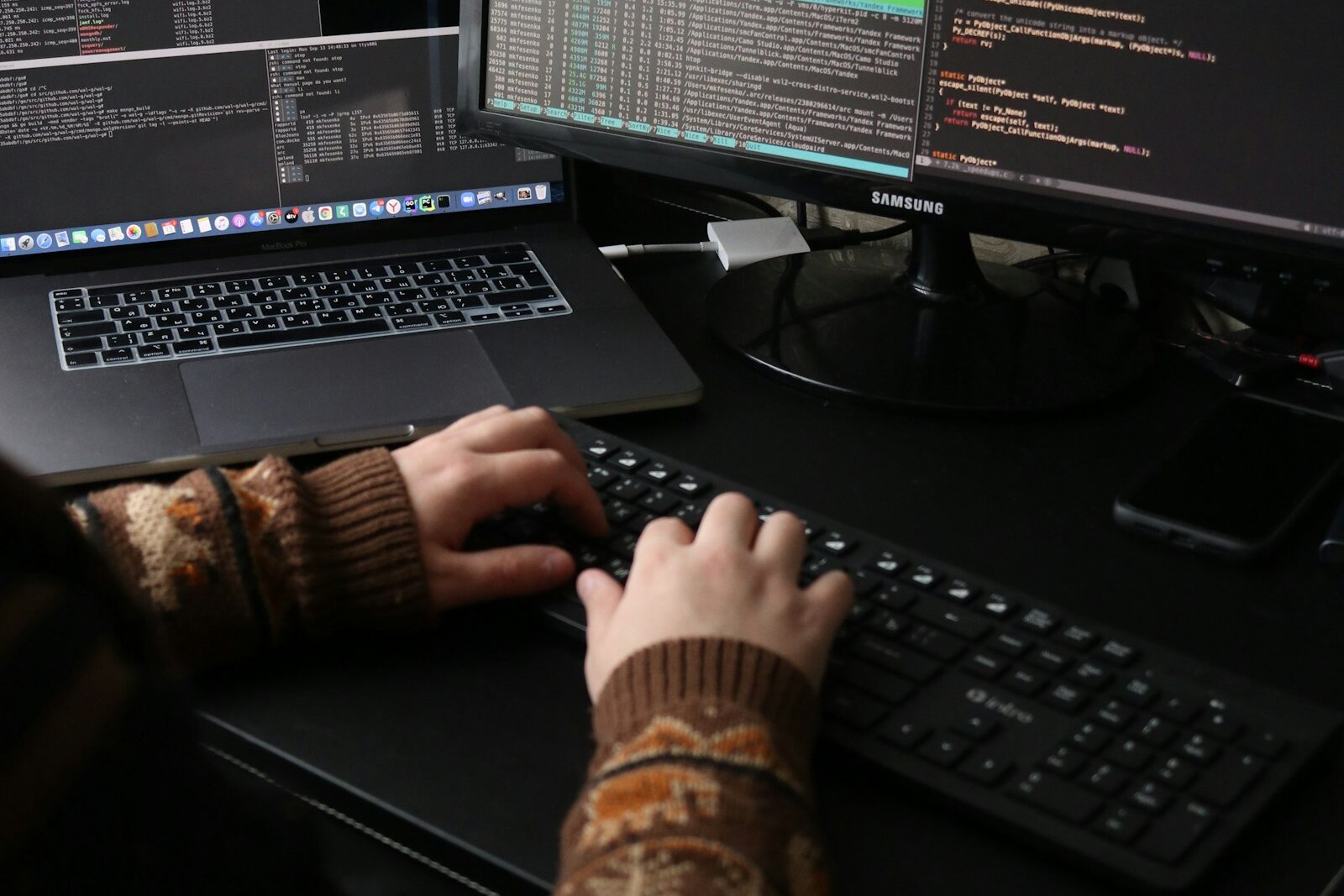 A senior engineer working at a multi-monitor coding workstation